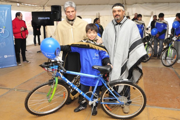 Poggi junto a un referente Ranquel entrega una bici a uno de los niños