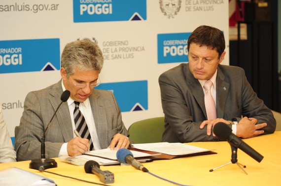Poggi firma los decretos, a su lado el director de Vialidad Nacional