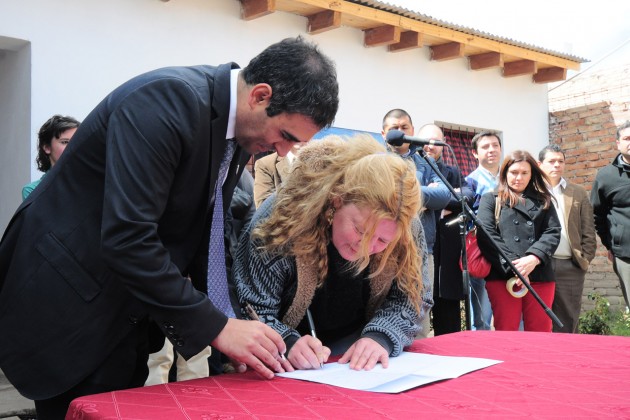 La feliz propietaria firma el acta de entrega