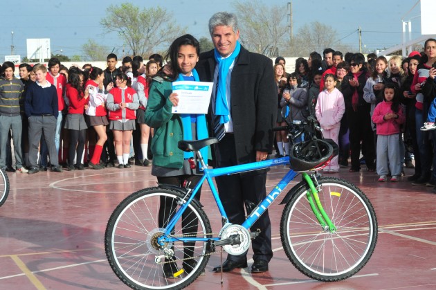 Poggi entrega una bici a u alumno del Colegio Martín de Guemes