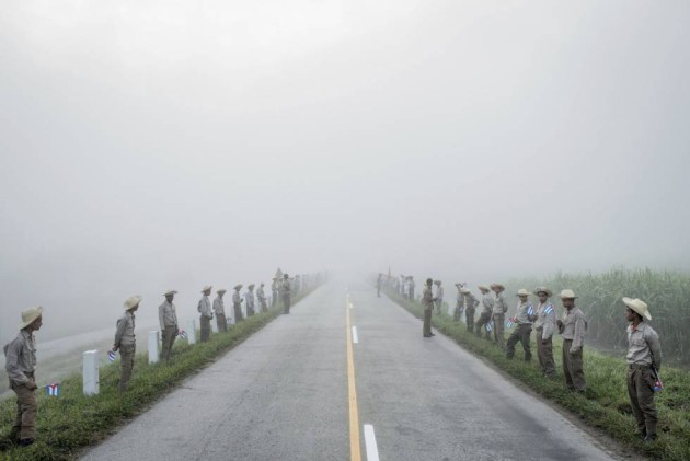 18- Instantánea ganadora del primer premio en el apartado Historias de la categoría “Vida Cotidiana”, del fotógrafo del The New York Times, Tomás Munita. La imagen muestra a miembros del Ejercito Juvenil del Trabajo, alineados en una carretera de Santiago de Cuba mientras aguardan la llegada de los restos mortales del líder cubano, Fidel Castro.